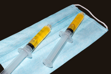 Syringes with blood plasma on a medical protective mask. Blood plasma as coronavirus treatment...