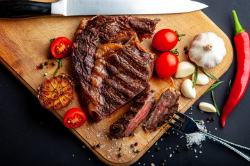 Fresh juicy ribeye steak with a set of spices on a cutting board