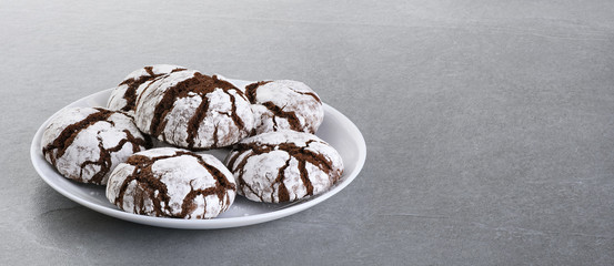 Chocolate chip cookie with cracks on a gray background.