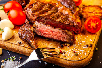 Fresh juicy ribeye steak with a set of spices on a cutting board