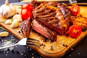 Fresh juicy ribeye steak with a set of spices on a cutting board