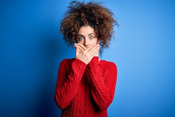Fototapeta na wymiar Young beautiful woman with curly hair and piercing wearing casual red sweater shocked covering mouth with hands for mistake. Secret concept.