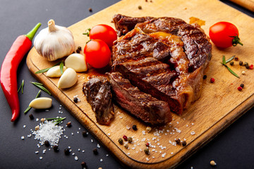 Fresh juicy ribeye steak with a set of spices on a cutting board