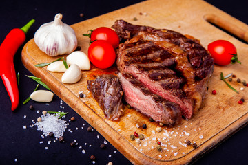 Fresh juicy ribeye steak with a set of spices on a cutting board