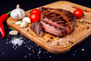 Fresh juicy ribeye steak with a set of spices on a cutting board