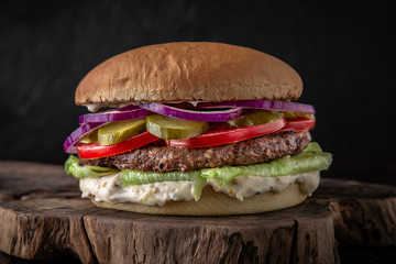 Delicious juicy cheeseburger from Brioche Bun, Aged beef cutlet, American Cheddar, Tomatoes, Gherkins, Red onions, Iceberg. Hamburger for poster or menu.