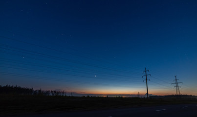 The sunset and the starry sky above the power lines.