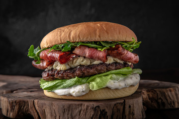 Delicious juicy burger from Brioche Bun, aged beef cutlet, bacon, Dorblu cheese, tomatoes, gherkins, iceberg, onion marmalade Hamburger for poster or menu. 