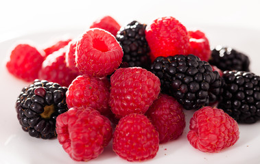 handful of raspberry and blackberry berries on white background