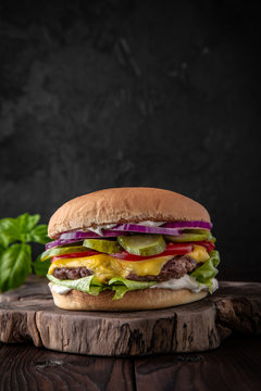 Delicious juicy cheeseburger from Brioche Bun, Aged beef cutlet, American Cheddar, Tomatoes, Gherkins, Red onions, Iceberg. Hamburger for poster or menu.