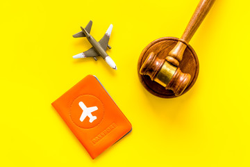 Flight cancellation. Airplane, passport, judge gavel on yellow desk top-down