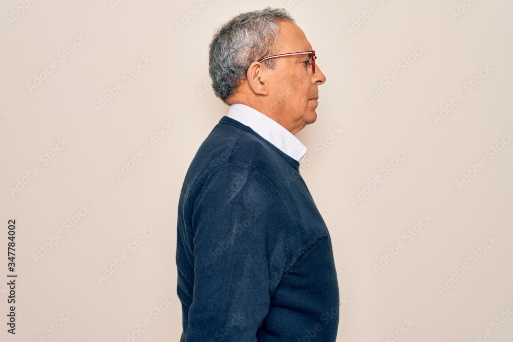 Wall mural senior handsome grey-haired man wearing sweater and glasses over isolated white background looking t