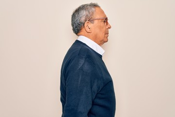 Senior handsome grey-haired man wearing sweater and glasses over isolated white background looking...