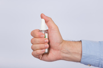 Male hand holds antibacterial spray on white background. Compact spray bottle in hand. Side view