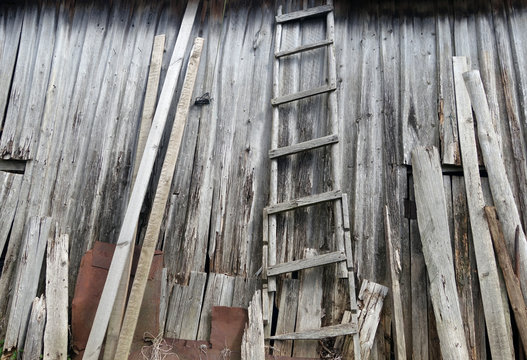 Old weathered wooden ledder in front of barn almost ruined.