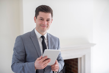 Portrait Of Male Realtor With Digital Tablet Looking Around And Valuing New Home