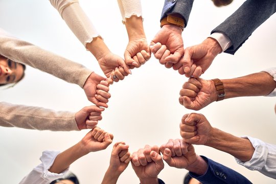 Group of business workers standing bumping fists at the office