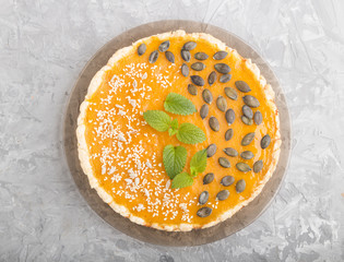 Traditional american sweet pumpkin pie decorated with mint, sesame and pumpkin seeds on a gray concrete background. top view, close up.