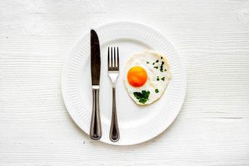Fried eggs on plate - white wooden table top view