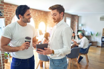 Business workers smiling happy. Standing with smile on face working together using tablet at the office