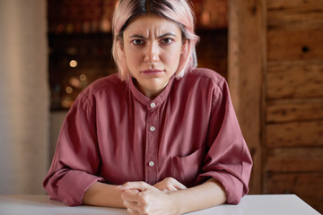 Webcam screen shot of displeased young woman working from home, looking at camera while communicating online using video conference chat, having angry facial expression, frowning, pumping fists