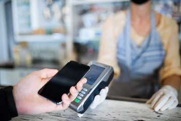 Contactless payment with smartphone, coffee shop open after lockdown.