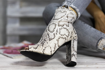 Luxury female high heel shoes made from snake skin worn by a woman