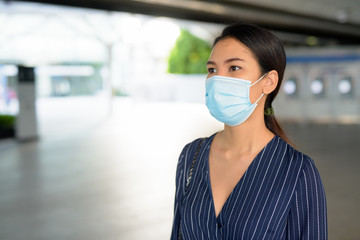 Fototapeta na wymiar Young Asian businesswoman with mask for protection from corona virus outbreak walking off from the train station