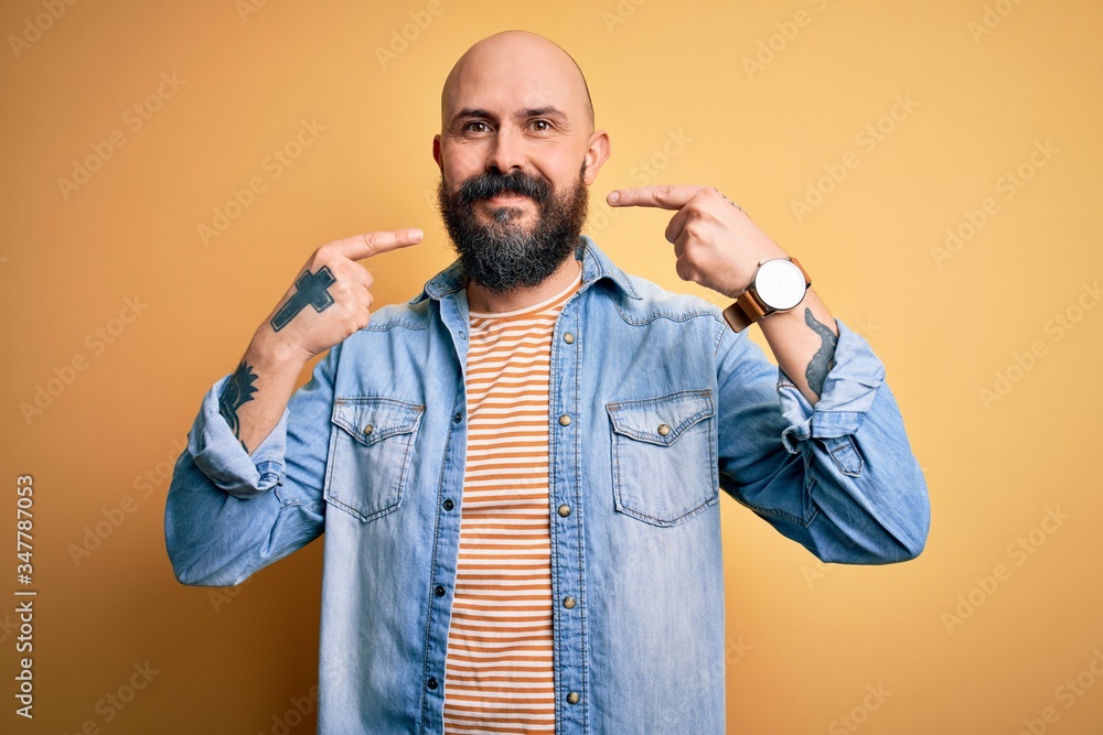 Canvas Prints Handsome bald man with beard wearing casual denim jacket and striped t-shirt smiling cheerful showing and pointing with fingers teeth and mouth. Dental health concept.