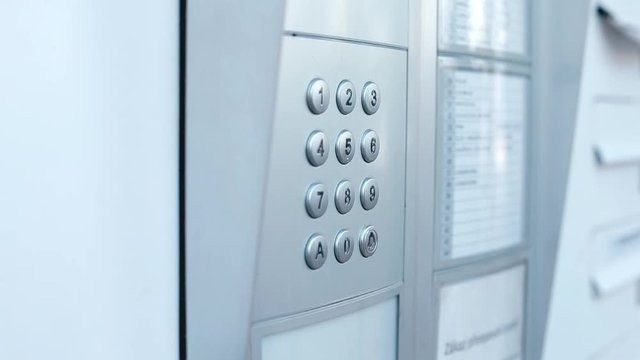 Male hand presses the buttons of the intercom of an apartment building. Transmission surface of the causative agent of an infectious disease COVID-19.