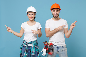 Funny couple woman man in casual clothes protective helmet hardhat isolated on blue background....