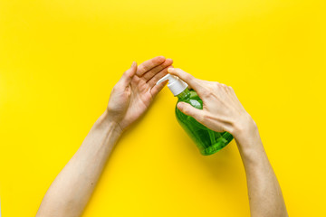 Disinfecting hands. Dispensing sanitizer on yellow background top view