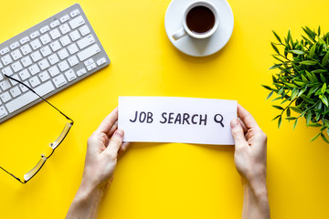 Job search. Text in hands on yellow office background top view