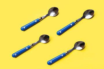 pattern of blue metal spoons on a yellow background shot from above