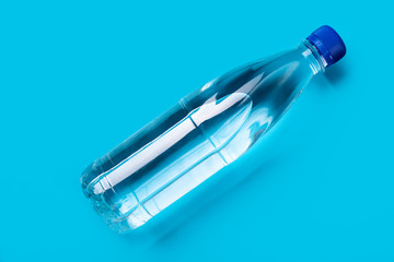 plastic bottle of water with a blue cap on a blue background shot from above