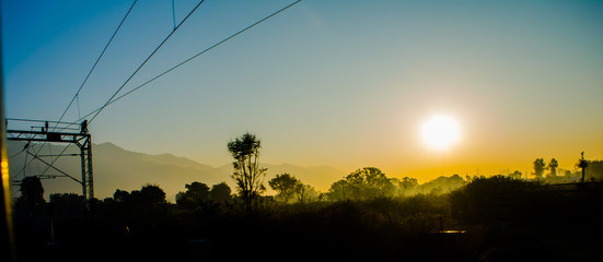 sun rays coming through the trees and electric towers with fog enhancing the light at sunrise, Aerial view
