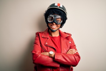 Young African American afro motorcyclist woman with curly hair wearing motorcycle helmet happy face smiling with crossed arms looking at the camera. Positive person.