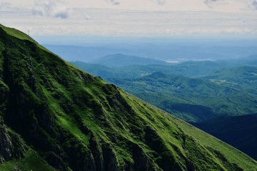 horizon seen from above in top of the mountain on summer day with white clouds and green grass