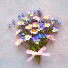 Spring bouquet with daisies, forget-me-nots, pansies on a colored background.