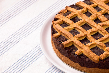 Close-up of fresh poppy seed cake on the plate. Homemade poppy cake lay on a table with tablecloth. Round, fresh pie ready to eat.