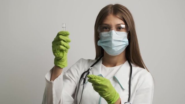 Girl doctor in a mask and gloves holds test tubes. Health, medical