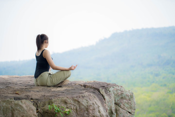 Fototapeta na wymiar young woman doing yoga exercise on the top of the mountain 