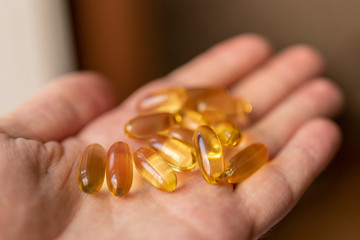 A handful of vitamin d capsules is in a man's hand. Blurred background