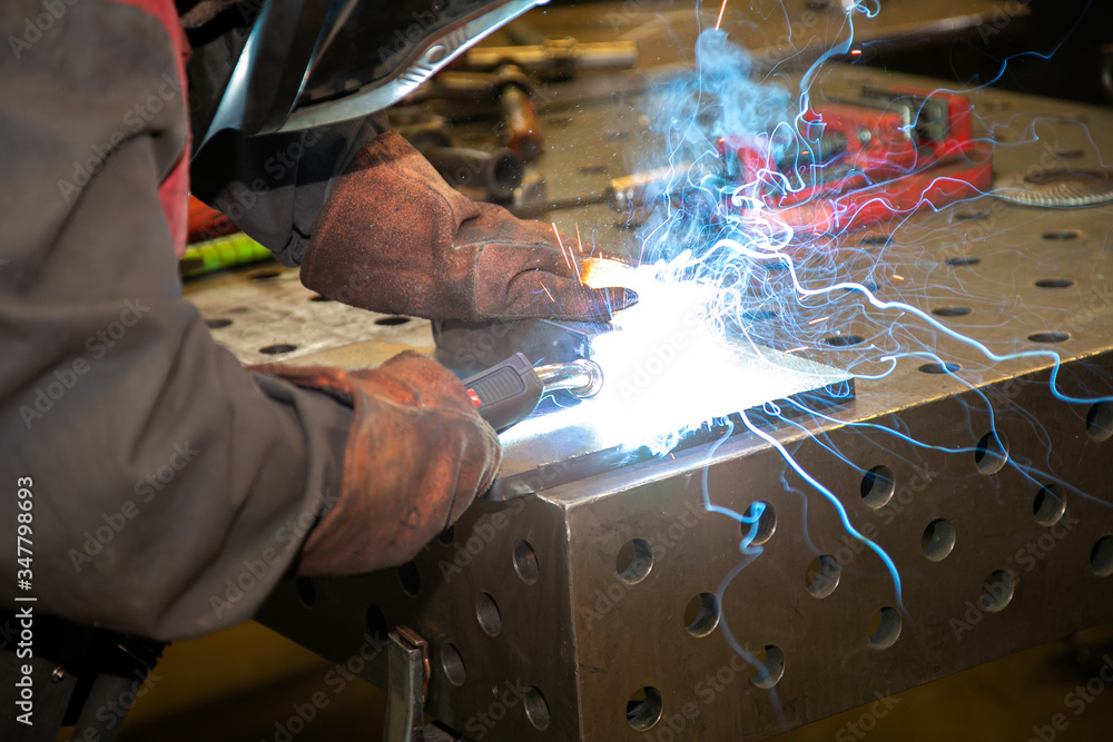 Wall mural welder welds a part on an industrial table