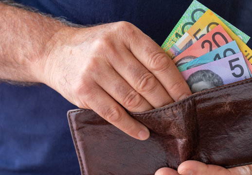 Male hand taking Australian bank notes out of brown wallet