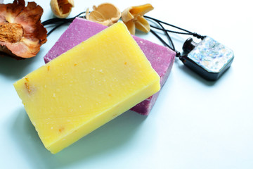 Homemade spa treatments concept. Fragrant natural soap, a bottle for essential oils and dried flowers on blue.