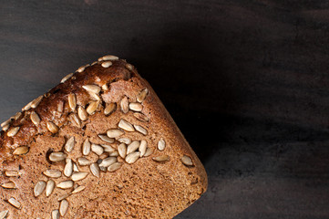 delicious fresh baked bread with bran sunflower seeds on a dark table, horizontal image