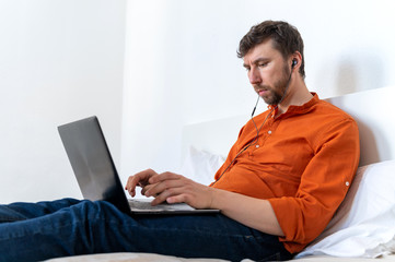 Freelancer working at home on sofa using laptop and headset