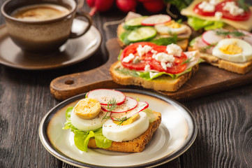 Toasts with eggs, cheese, ham, radish, cucumbers and tomatoes , breakfast idea.