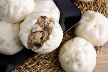 White buns on a black plate on a brown wooden floor.
